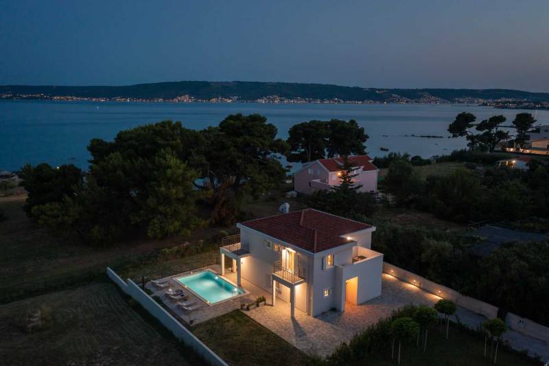 Villa Marella mit Pool in der Nähe von Trogir, umgeben vom Meer und Pinienwald, Luftaufnahme in der Abenddämmerung